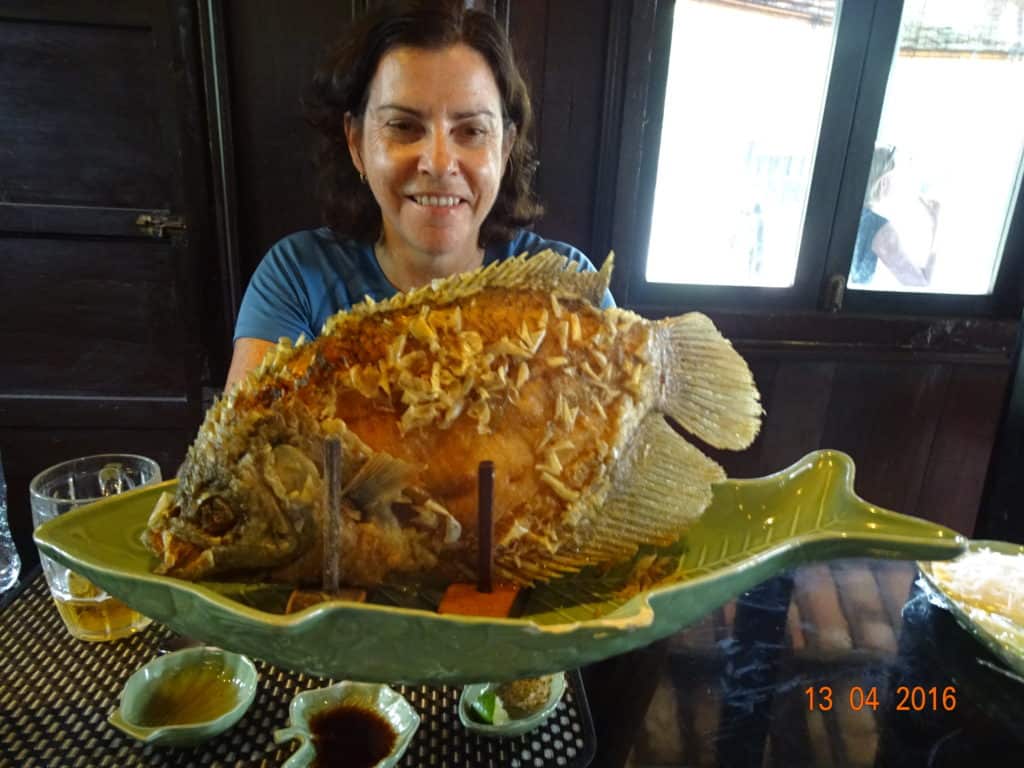Lady holding a large cooked fish
