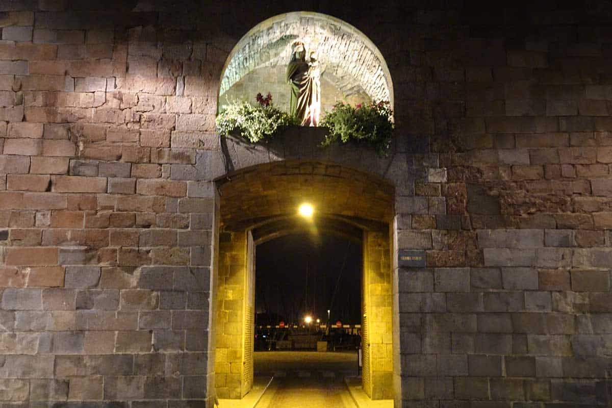 An exit through an old wall with a lit statue