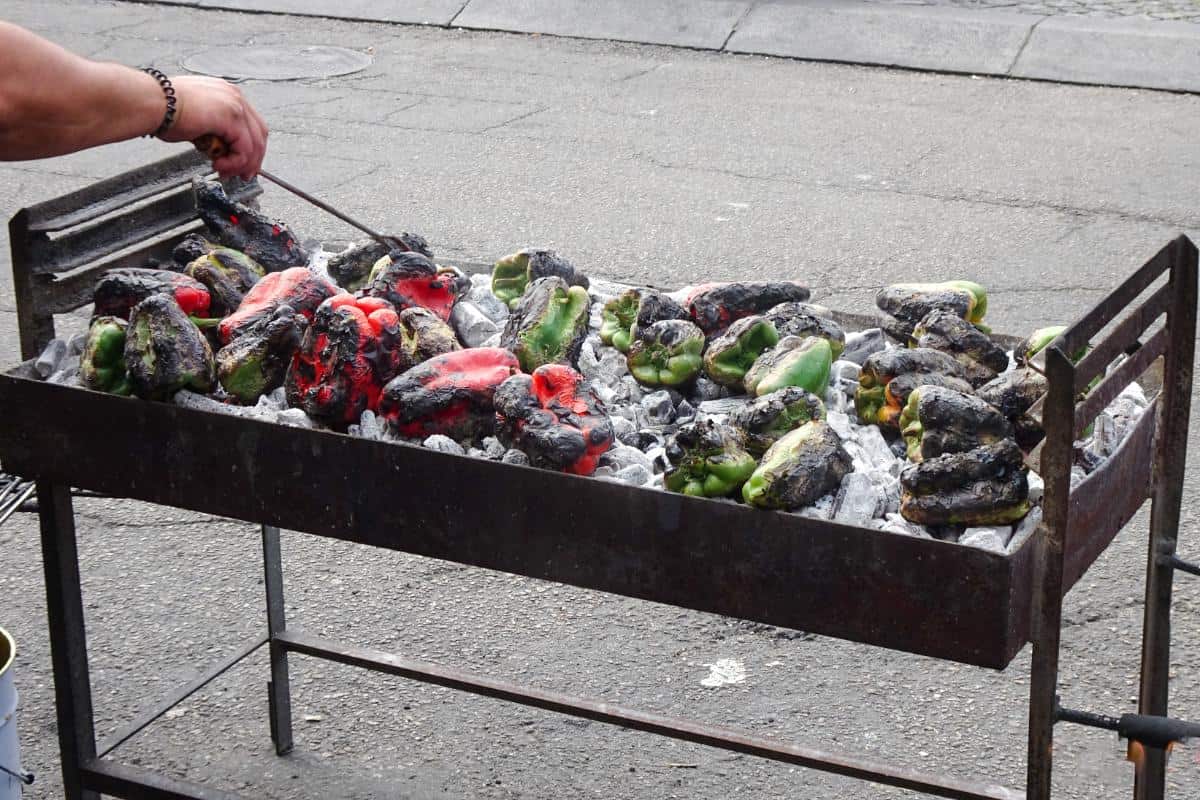 Red and green peppers being barbequed over coals