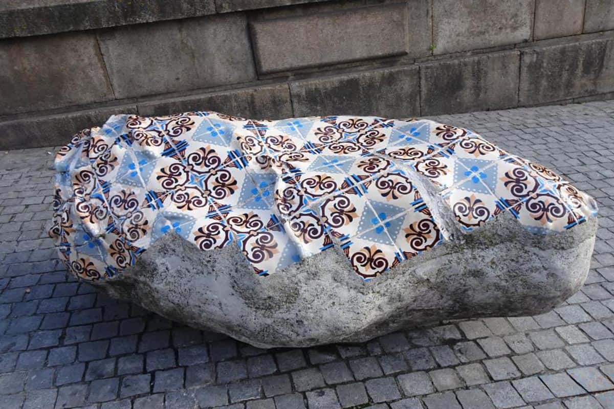 A large rock with blue and white tiles covering its surface