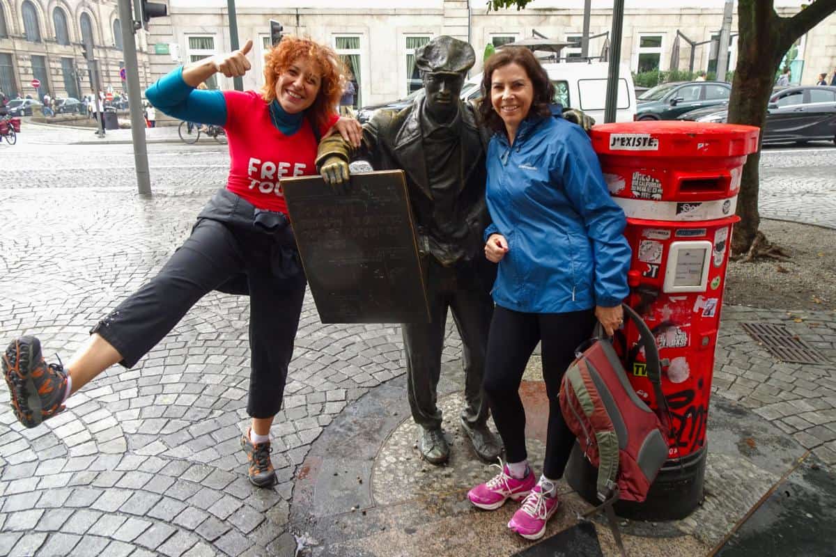 Two women next to a statue of a man and a post box