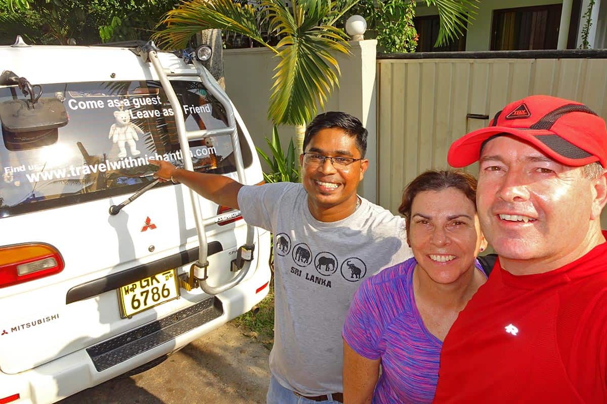 Three people at the back of as van sign written with travel information