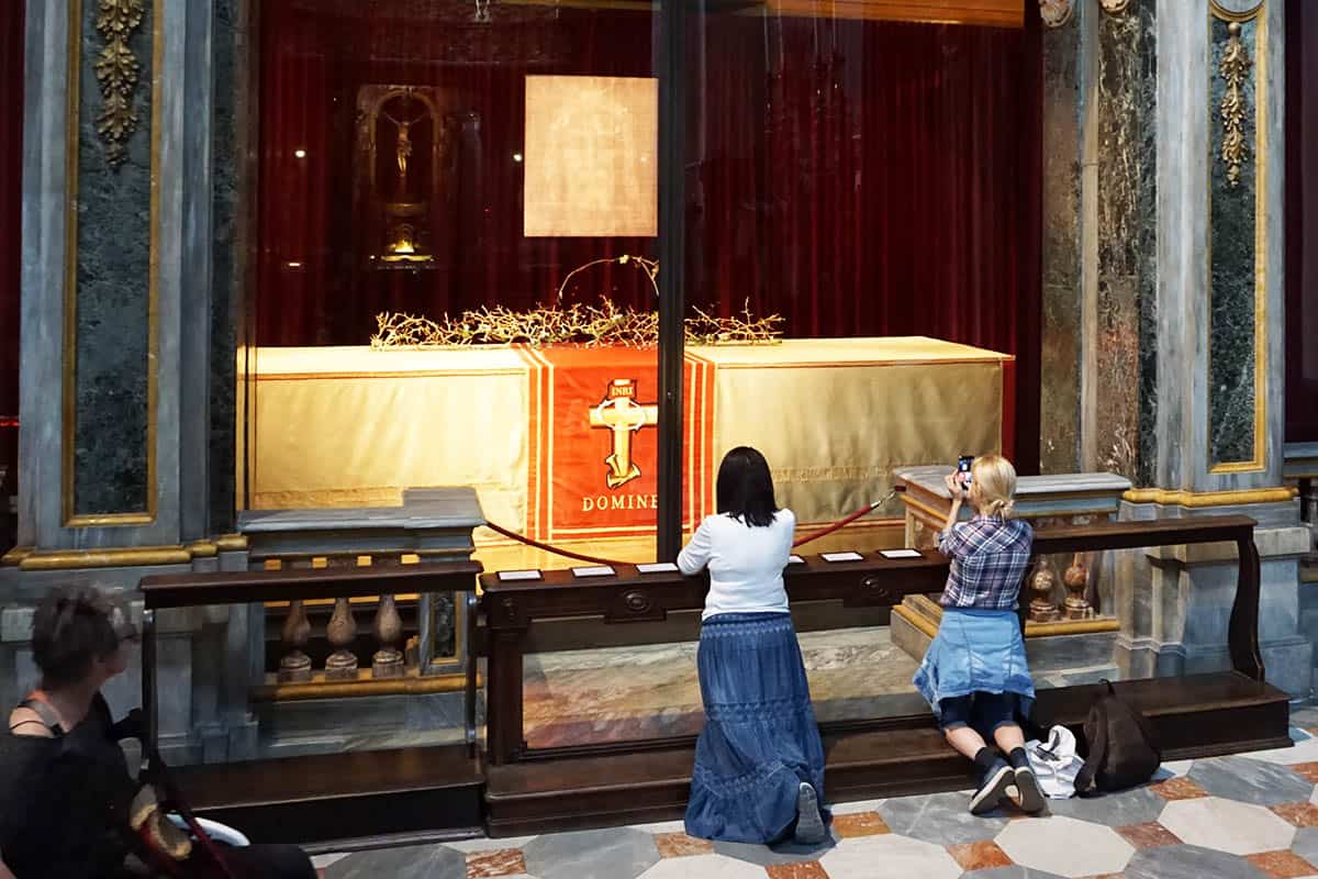 a person praying in front of the Shroud of Turin