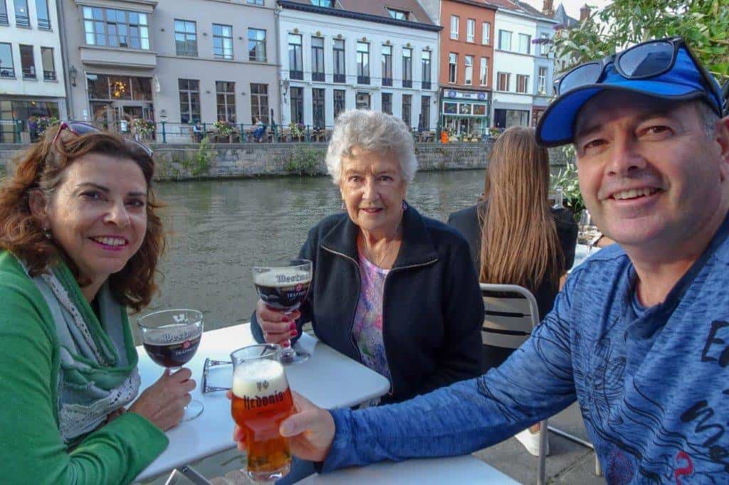 Three people enjoying a beer next to a canal