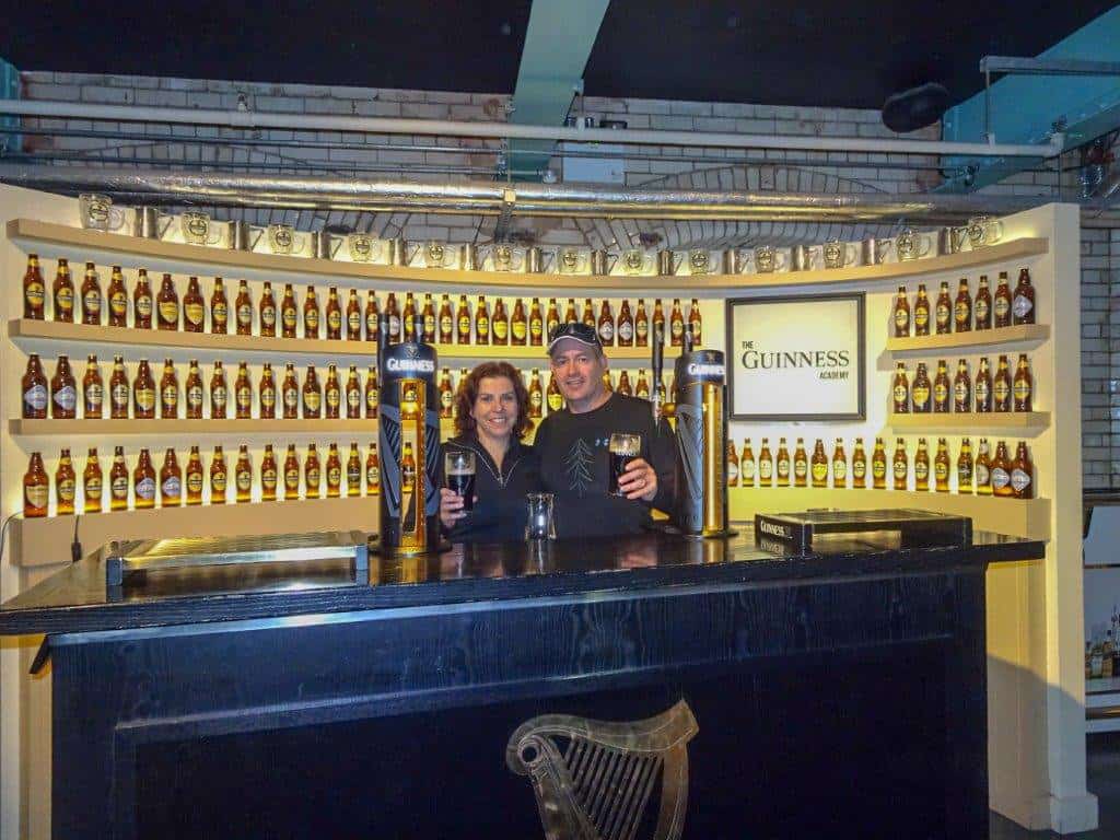 Man and Woman behind a bar with a row of bottles behind them