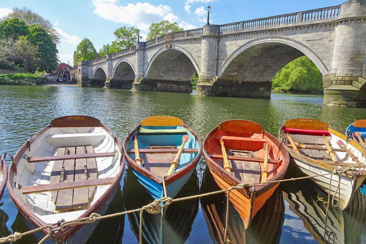 Colourful rowboats on a river with stone bridge