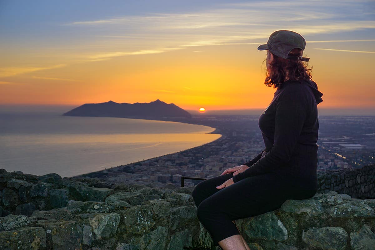 A woman looking at a sunset over a bay 