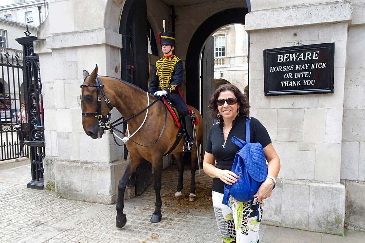 A woman standing near a horse with a soldier riding