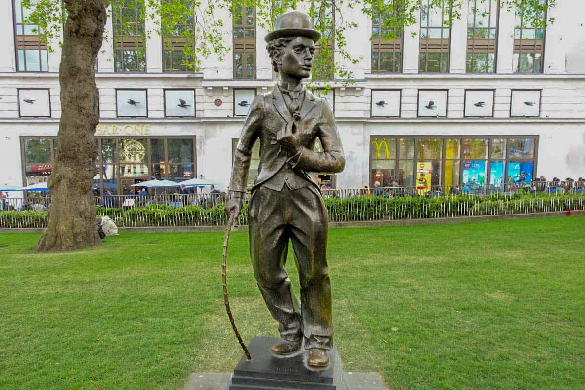 Statue of a man wearing a hat and carrying a walking cane