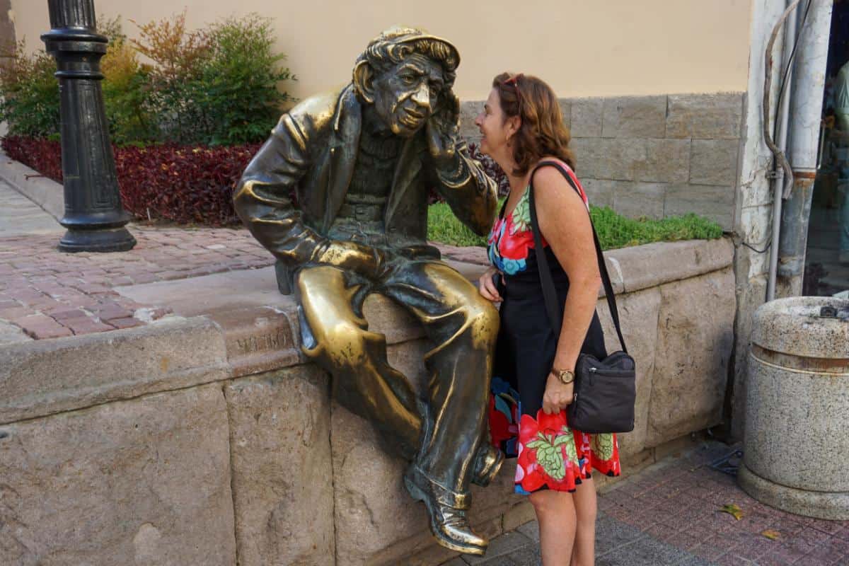 A lady whispering in the large ears of a statue