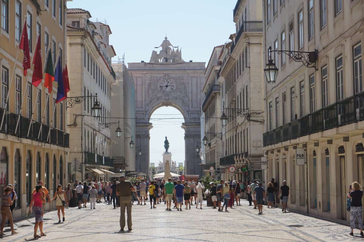 A busy pedestrian street with a huge arch at the end
