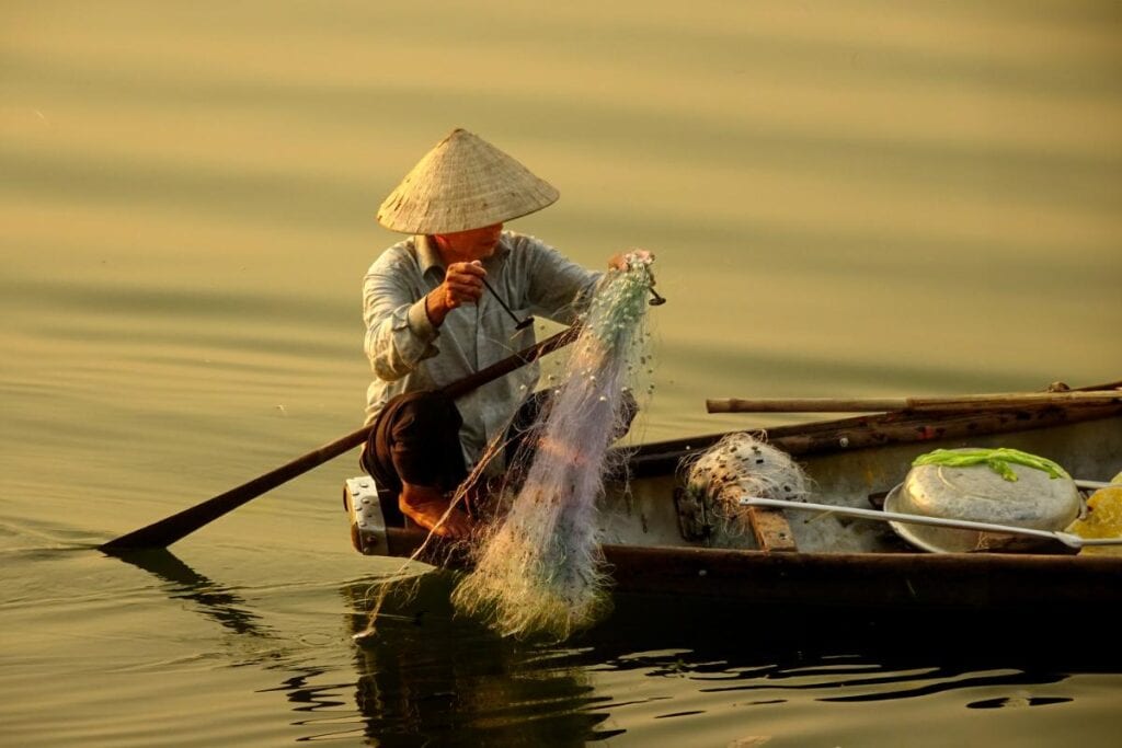 Man fishing off a boat in a river