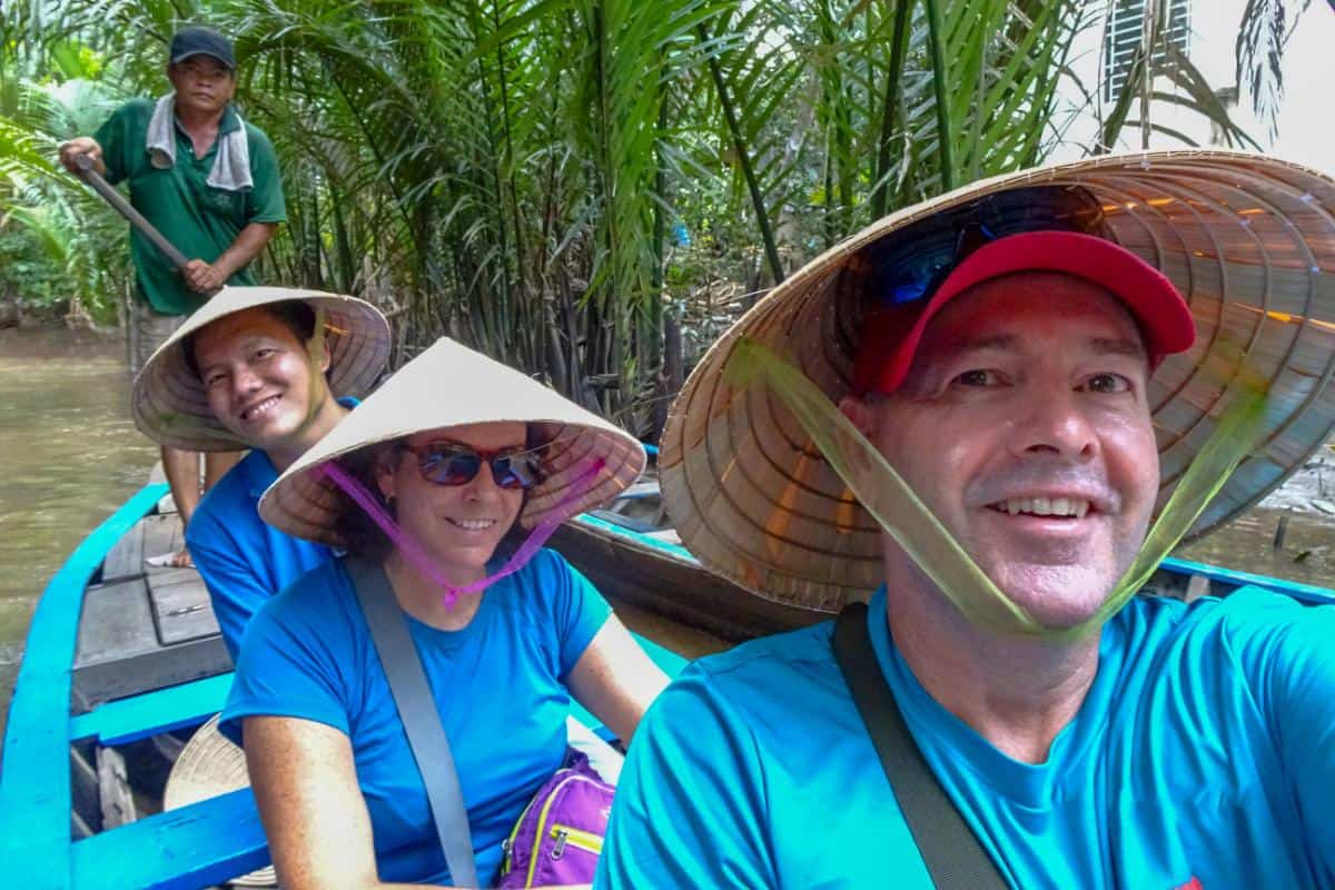 3 people on a canoe on a bamboo lined river