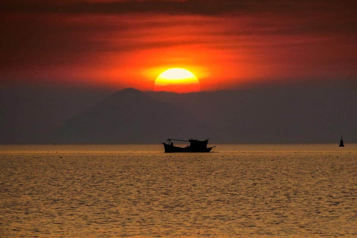 A fishing boat silhouetted against the setting sun