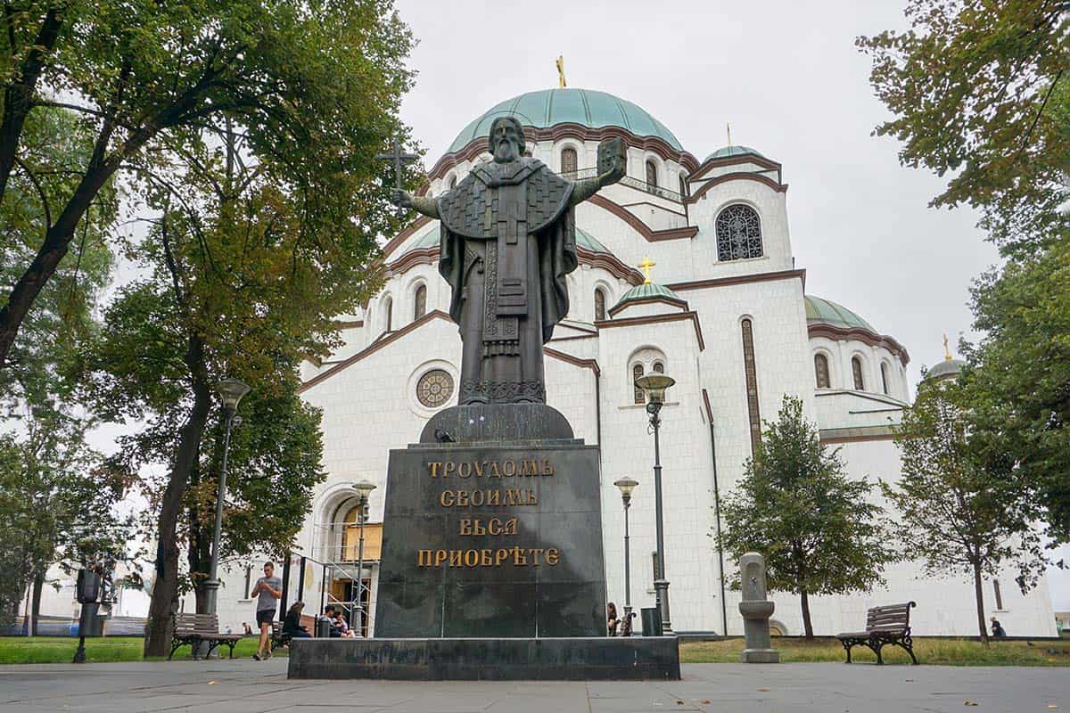 Statue in front of large white orthodox church with a green dome