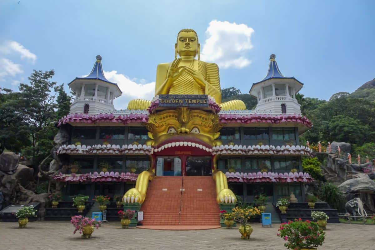 A gold colored Buddha statue above b uildings
