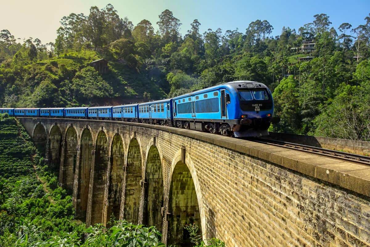 A blue train crossing an arched bridge