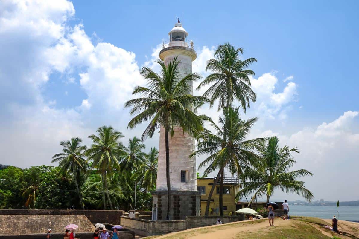 A white lighthouse surrounded by palm trees