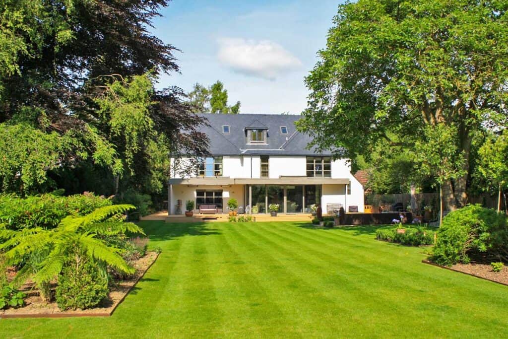 A large house set back beyond a large green lawn