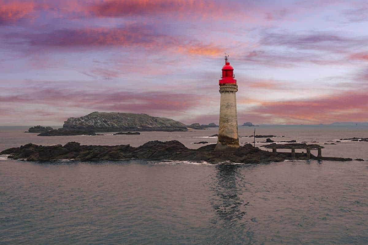 A red and white lighthouse at sunset