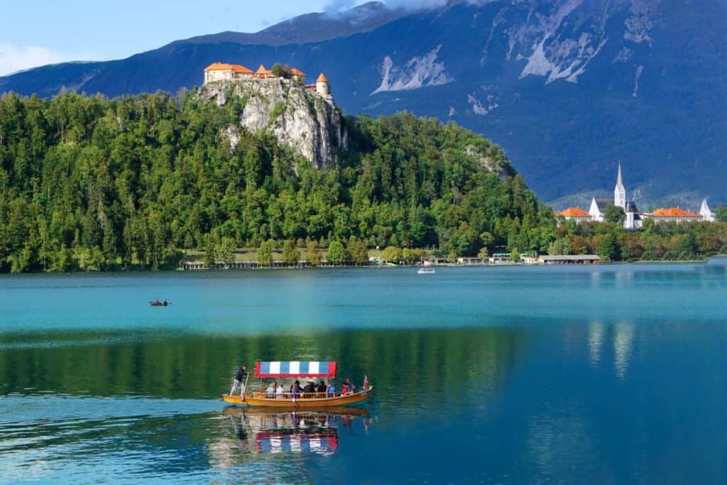 A boat carrying passengers on a lake with a castle in the background